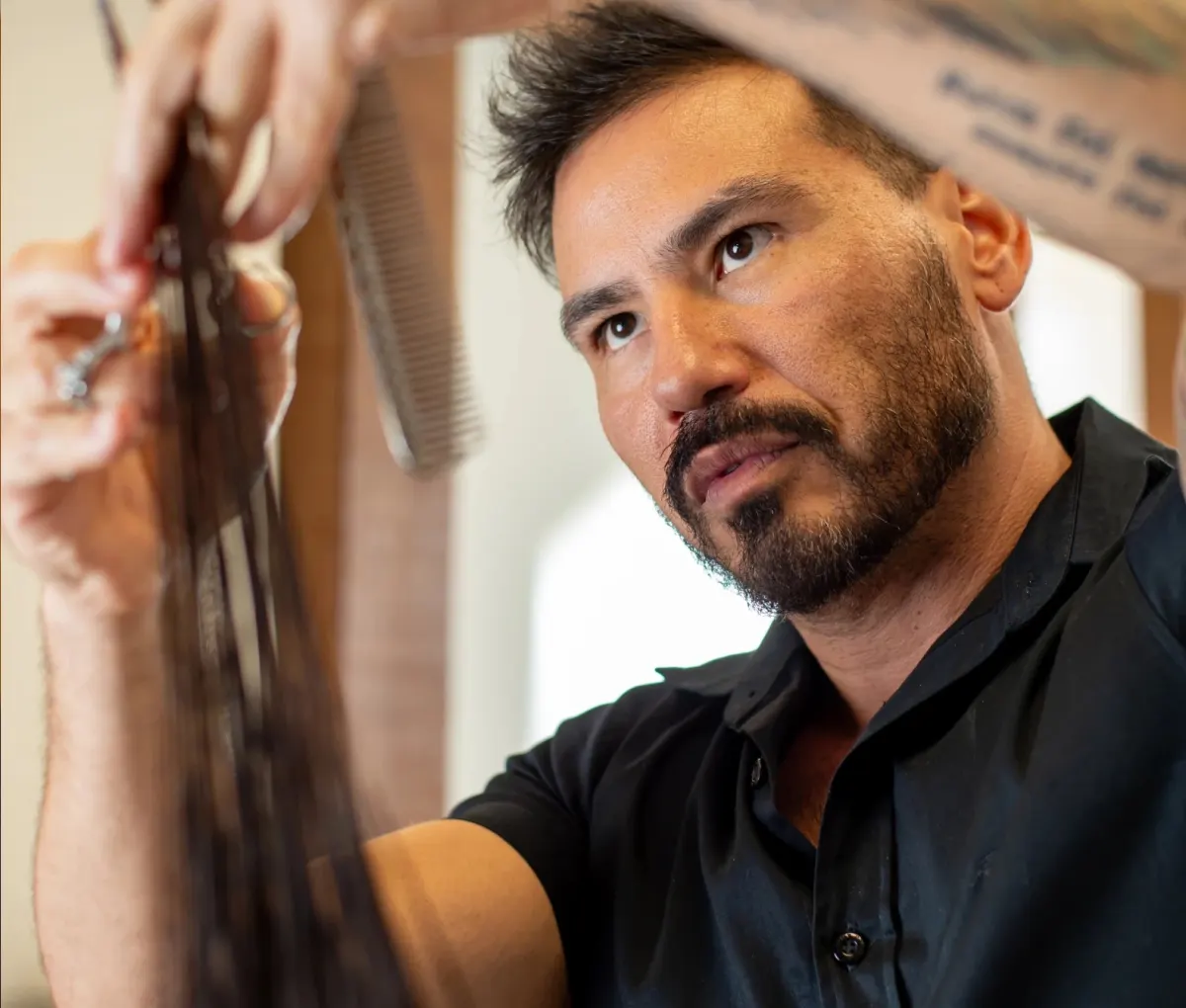 Fábio Matsuno observando atentamente uma mecha de cabelo durante um atendimento