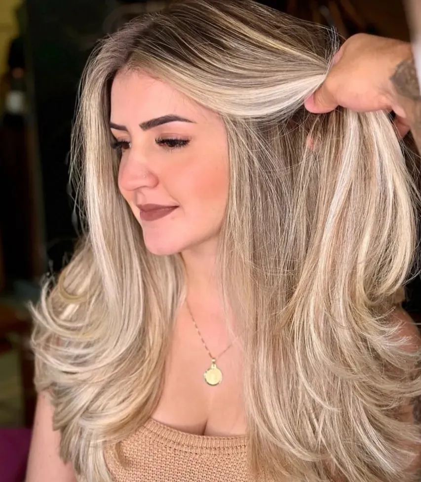 Mulher de perfil com cabelo longo em camadas e tons loiros iluminados, finalizado no salão Matsunos